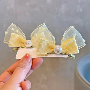 Detailed view of handmade light yellow lace bow hair clip with faux pearl accents
