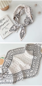 Detail of pleated beige silk scarf with paisley pattern and elegant necktie styling
