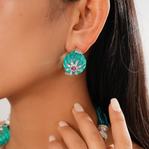 Close-up of turquoise shell-shaped earring with crystal flower motif on model