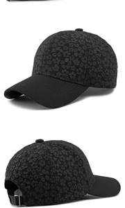 Détail d'une casquette noire à motif floral avec texture en relief et boucle en métal