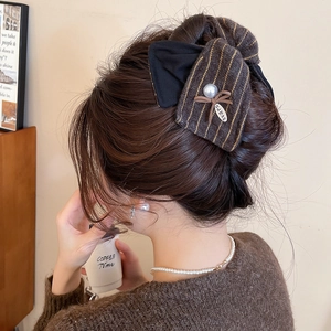 Détail de la pince à cheveux nœud tricoté avec perle portée par un mannequin de profil