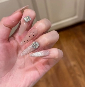 Detail of long almond press-on nails with nude cat-eye finish and rhinestones