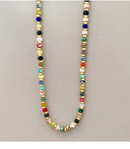 Detail view of handmade necklace with colorful square stones and golden beads