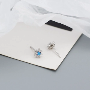 Close-up of daisy stud earrings with silver metal and blue opal stones with zircons