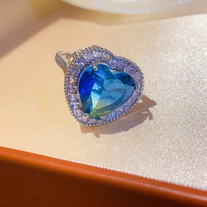 Macro shot of silver ring featuring heart-shaped blue stone and halo diamond accents