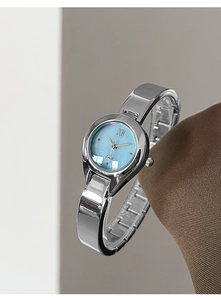 Detail view of silver bangle watch with light blue dial and Roman numerals at 45 degrees