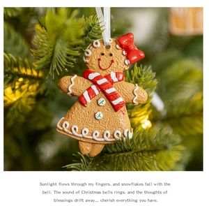 Cute gingerbread girl ornament with red bow hanging on a festive Christmas tree branch