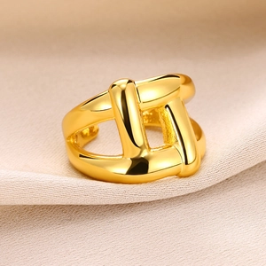 Macro shot of gold-plated chunky geometric knotted ring on luxury beige silk fabric