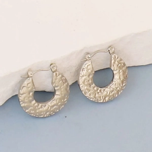 Detailed view of irregular hammered texture on geometric C-shaped hoop earrings