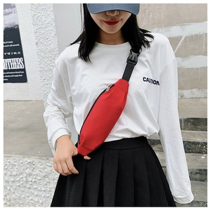 Detail of red canvas waist bag with zipper closure and adjustable black shoulder strap