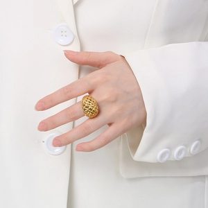 Detail of a textured diamond-patterned gold ring worn on a model in formal attire