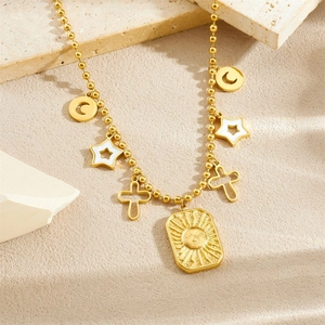 Gold beaded necklace with sun, star, moon, and cross pendants on beige textured stone
