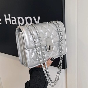Detail of silver quilted leather texture and metal twist lock on the crossbody bag