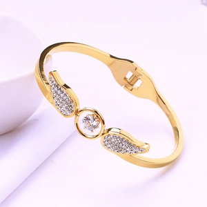 Detailed shot of gold angel wing bangle with sparkling zircon stones and polished finish