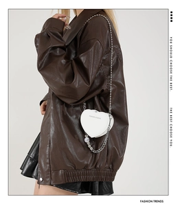 Close-up of heart-shaped white PU leather crossbody bag with silver chain and pearl charm