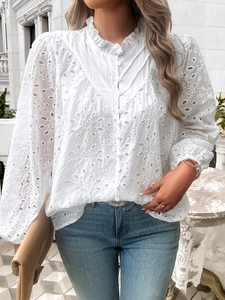 Detail of white hollow embroidery on a long sleeve shirt with a stylish ruffle stand collar