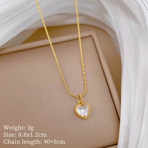 Macro shot of gold heart pendant with clear crystals on a beige jewelry box
