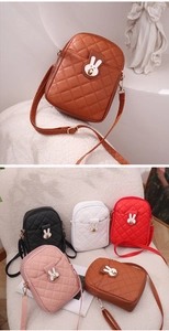 Detail of a quilted mini crossbody bag featuring a cute white rabbit metal twist lock buckle