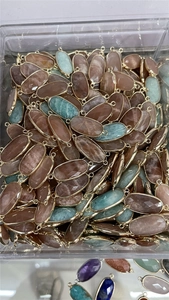 Detail of oval crystal charms with gold-plated edges and double connectors in assorted colors