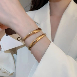 Close-up of polished gold-plated metal bangles with geometric double-layer design