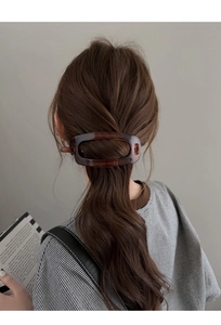 Détail d'une barrette ovale en résine écaille sur cheveux bouclés pour un look chic