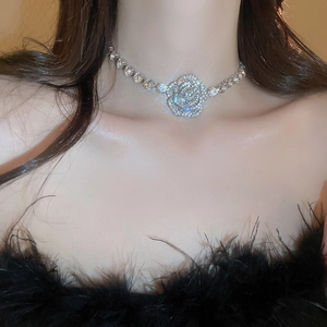 Close-up of sparkling rhinestone rose necklace on model wearing black feather top
