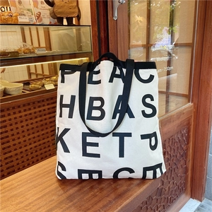 Detail of a large white canvas tote bag with black letter logo on a bakery counter