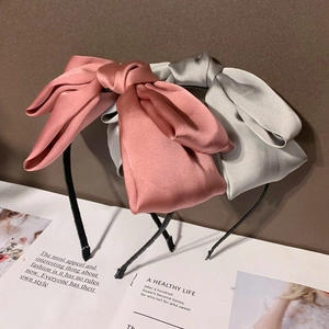 Vue détaillée de serre-têtes en satin rose et argent avec grand nœud sur papier vintage