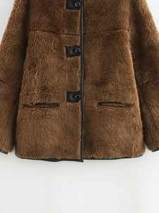 Detailaufnahme der braunen Kunstpelzjacke mit schwarzen Lederpaspeln und Knopfverschluss