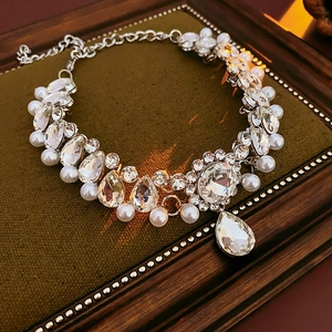 Close-up of sparkling floral waterdrop pearl necklace on a vintage green velvet surface