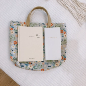 Detail of floral tote bag showing brown leather handles and sturdy metal rivets