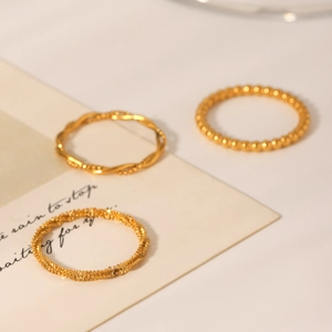 Close-up of three-piece gold-plated twisted rope and beaded ring set on elegant card