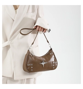 Detail of brown leather underarm bag with silver star charm and metallic rivets