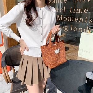 Floral corduroy tote bag with woven label shown in a stylish outdoor cafe setting