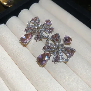 Elegant silver bow earrings with pink heart crystals and tassels in a velvet box