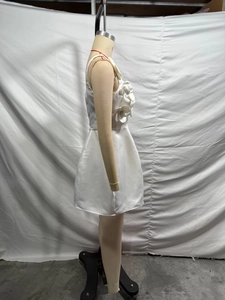 Vista laterale del mini abito in raso bianco con grandi fiori 3D e silhouette a trapezio