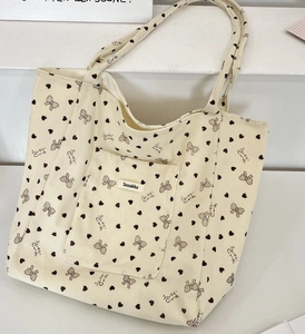 Detail of beige corduroy tote bag showing heart patterns and front storage pocket