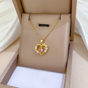 Macro view of gold heart pendant with pink gemstone and small bowknot detail