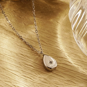 Elegant silver teardrop star pendant necklace with cubic zirconia on textured background