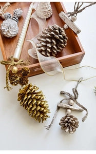 Close-up of golden pinecones, white spiral candles and wooden tray for Christmas decor