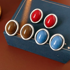 Detail of retro oval resin earrings in red, brown, and blue on a jewelry box