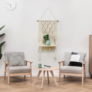 Detail of hand-woven cotton macrame wall shelf with wooden board in a cozy living room setup