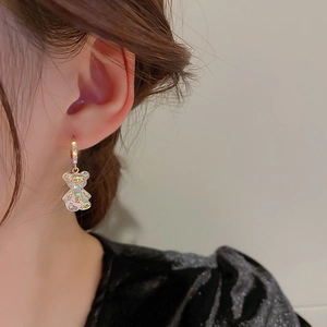 Close-up of aurora acrylic bear pendant earring worn on ear with golden hoop detail