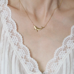 Minimalist whale pendant necklace in 18K gold plated titanium steel worn on white lace