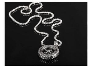 Macro detail of punk tire wheel pendant with cross star motif and blackened silver finish