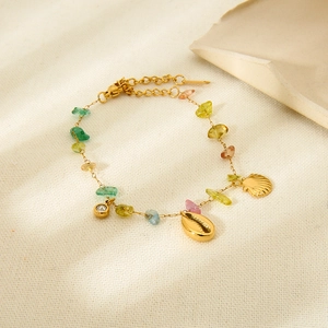 Detail of 18K gold-plated bracelet with sea shell charm and colorful stones