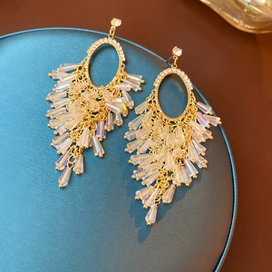 Macro shot of gold tassel drop earrings with sparkling crystals on a blue tray
