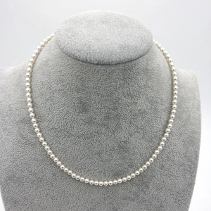Close-up of high-luster round white pearl necklace displayed on a gray velvet bust
