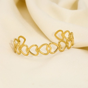 Macro shot of gold-plated stainless steel open cuff with hollow heart pattern