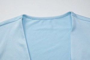 Détail de l'encolure ronde et des coutures sur une robe sans manches bleu clair en maille